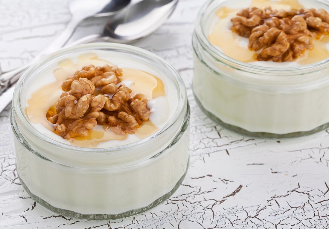 Natural yogurt with walnuts and honey in jars on a wooden table