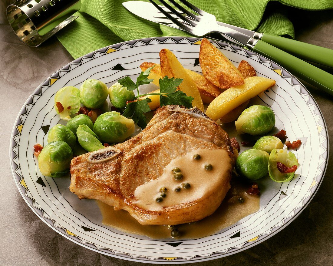 A pork chop in pepper sauce with brussel sprouts & potatoes