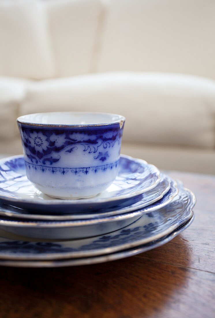 A stack of blue and white plates with a cup on top