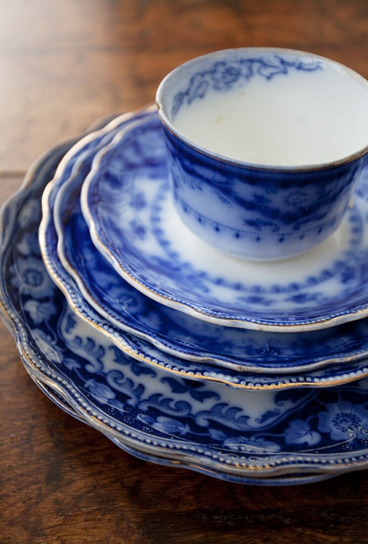 A stack of blue and white plates with a cup on top