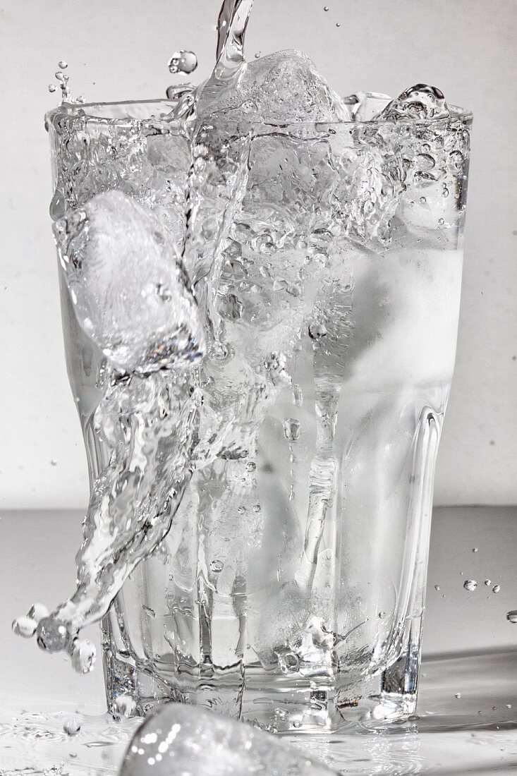 Water being poured into a glass of ice cubes