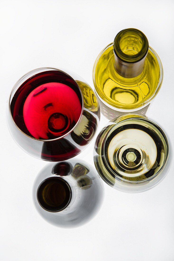 A glass of red wine, a glass of white wine and wine bottles