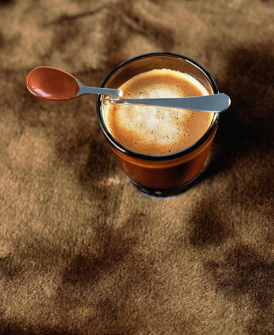 Löffel mit Schokolade auf einem Glas Cappuccino