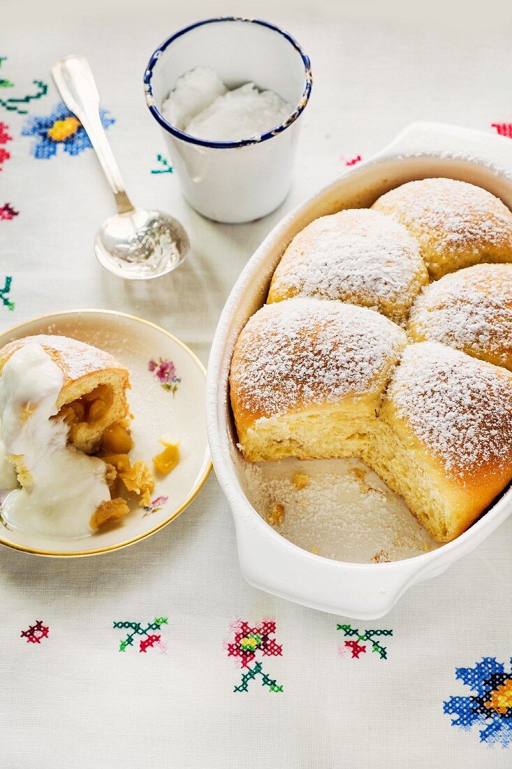 Apple filled Buchteln (baked, sweet yeast dumpling) with icing sugar and vanilla sauce