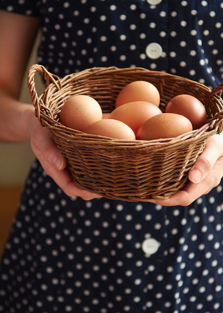 Frau hält Körbchen mit frischen Hühnereiern