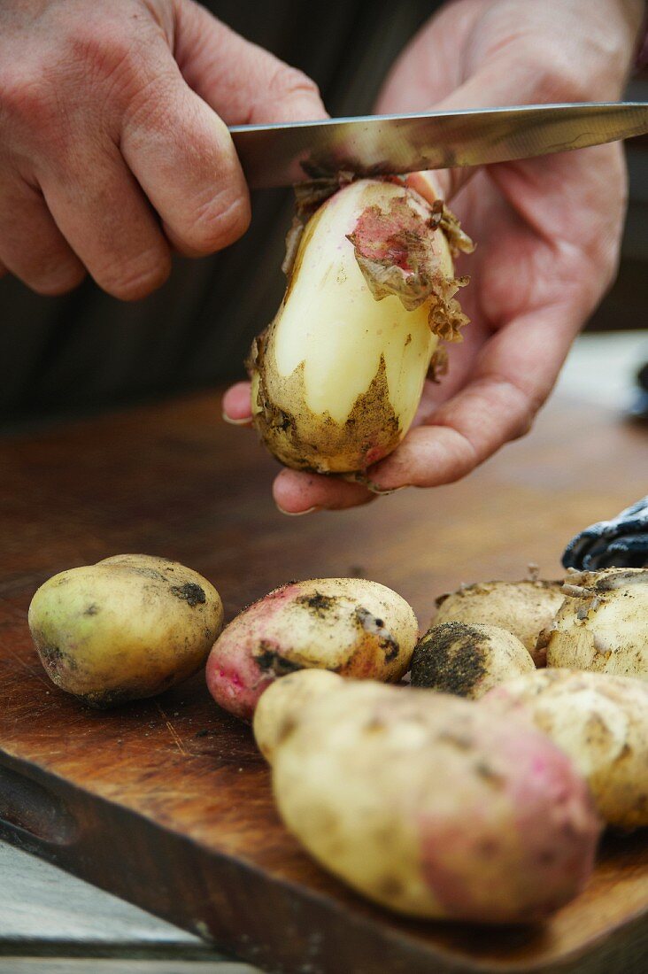 Kartoffeln auf dem Schneidebrett schälen