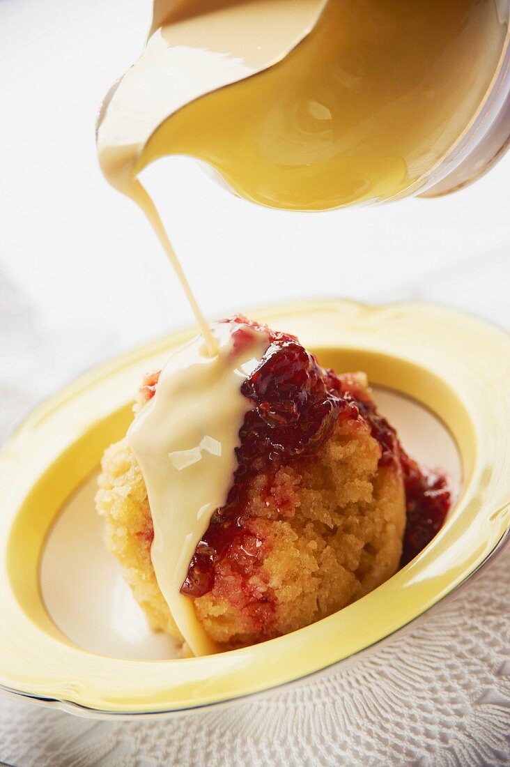 Vanillesauce auf gedämpften Pudding mit Marmelade gießen