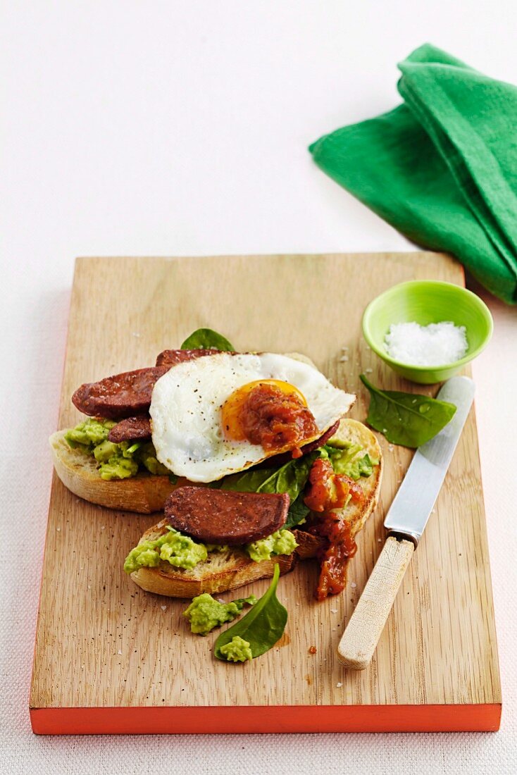 Toasted bread topped with chorizo, fried egg and avocado cream