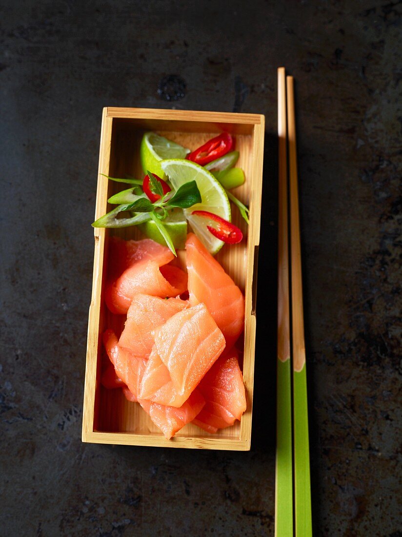 Salmon sashimi with limes in a wooden box (Japan)