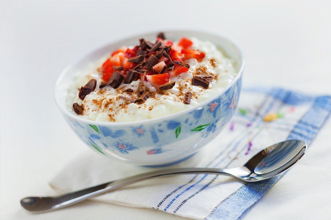 Rice pudding with grated chocolate, strawberries and cinnamon