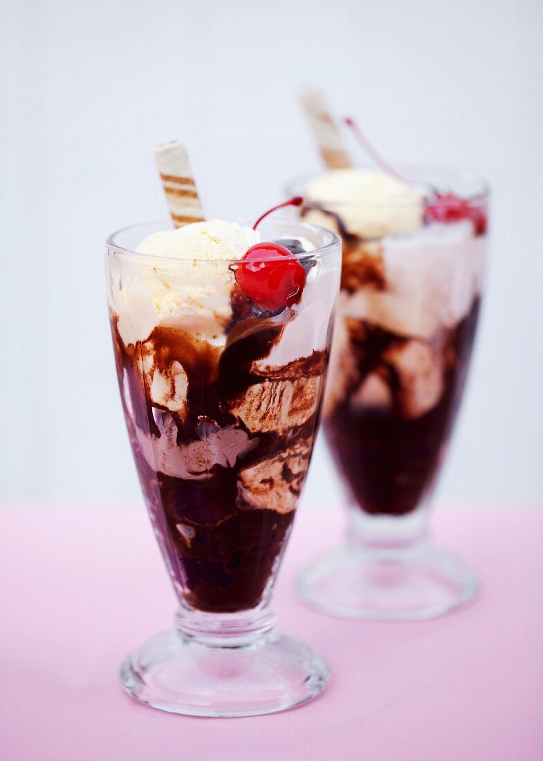 Schokoladen-Vanille-Eisbecher mit Cocktailkirschen und Waffelröllchen