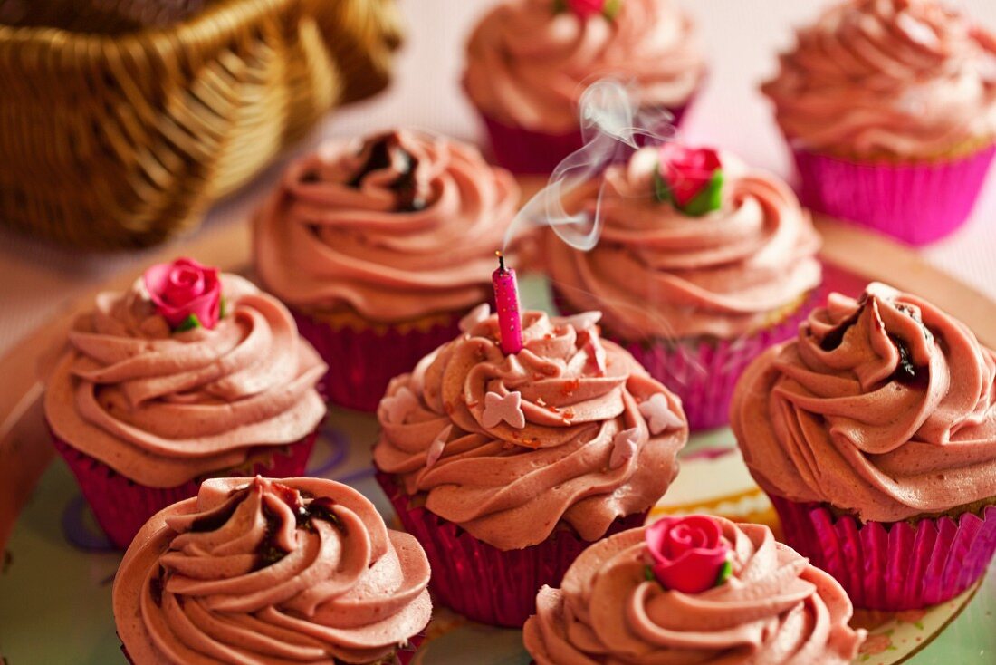 Cupcakes mit rosa Buttercreme und einer ausgeblasenen rauchenden Kerze