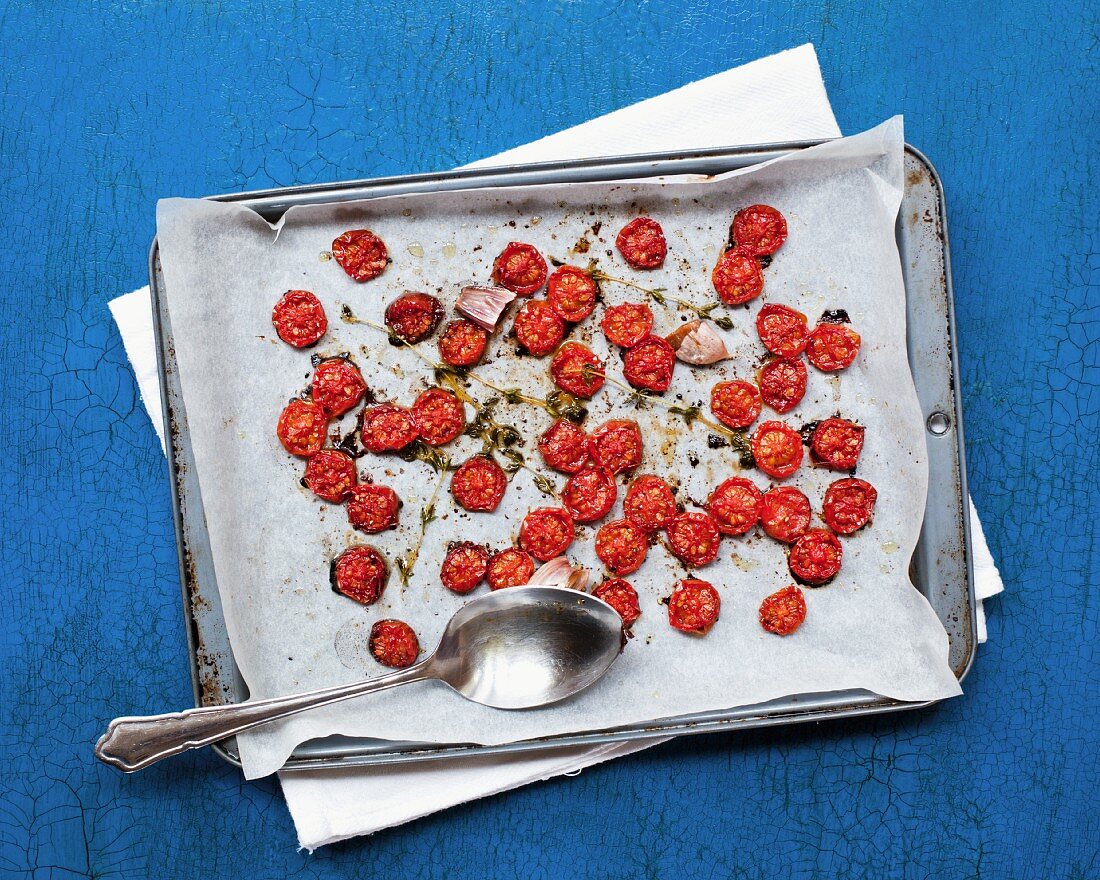 Slow roasted tomatoes, thyme and garlic on a baking tray