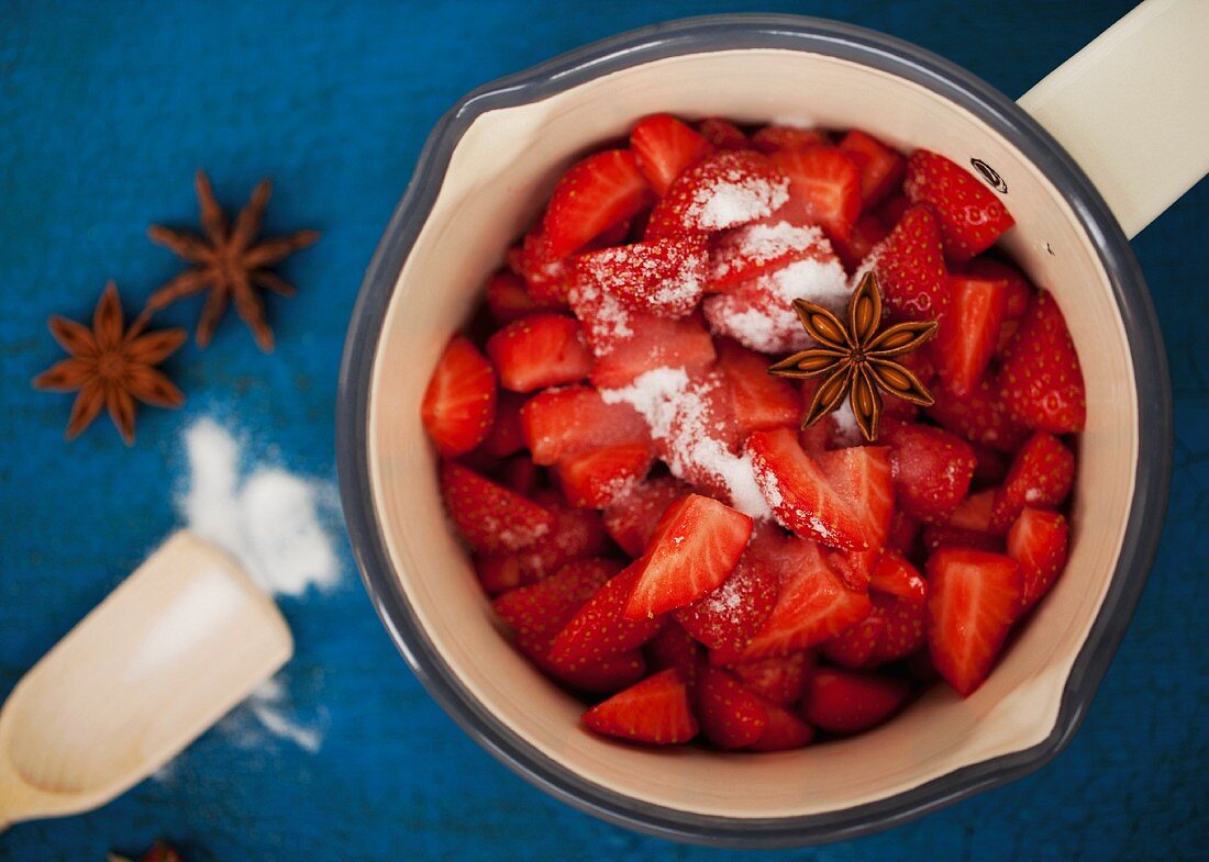Geschnittene Erdbeeren im Topf mit Zucker und Sternanis
