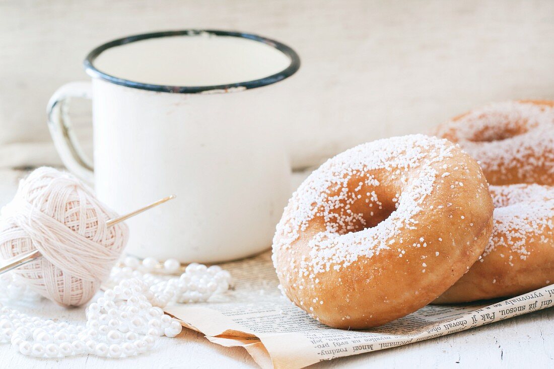 Sugar doughnuts and a white vintage mug on an old newspaper