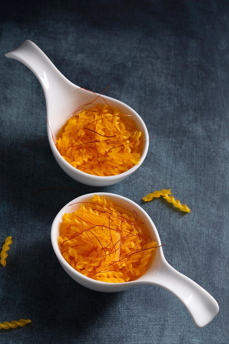 Two spoons of organic spirelli made from corn flour with saffron threads (gluten free)