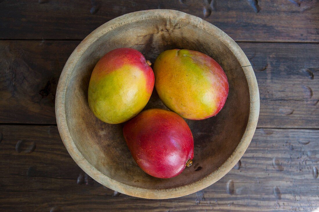 Ripe mangos in a wooden bowl