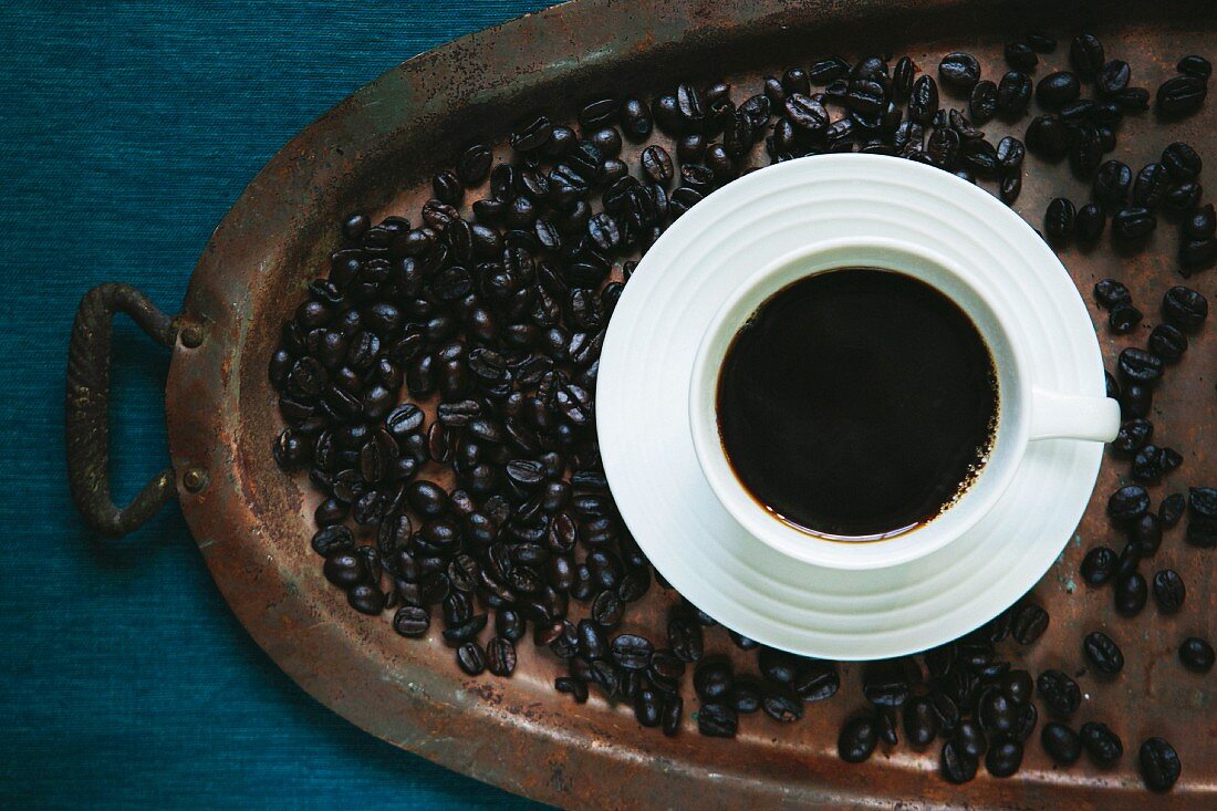 A cup of black coffee and coffee beans