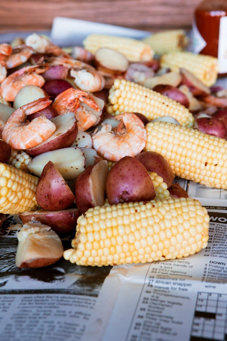 Boiled potatoes with corn cobs, sausage and prawns