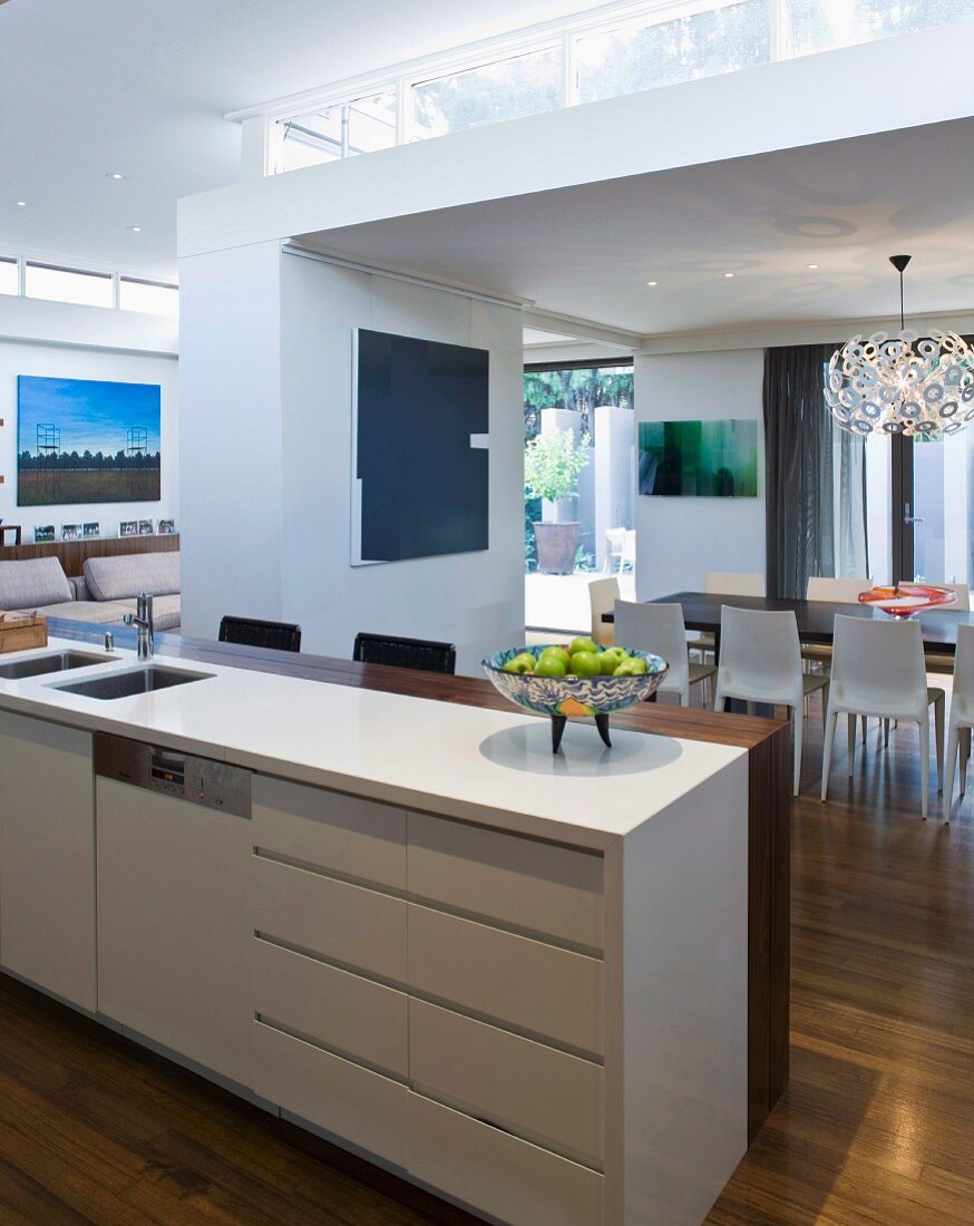 View across kitchen counter with breakfast bar into open-plan interior with ceiling zones of different heights