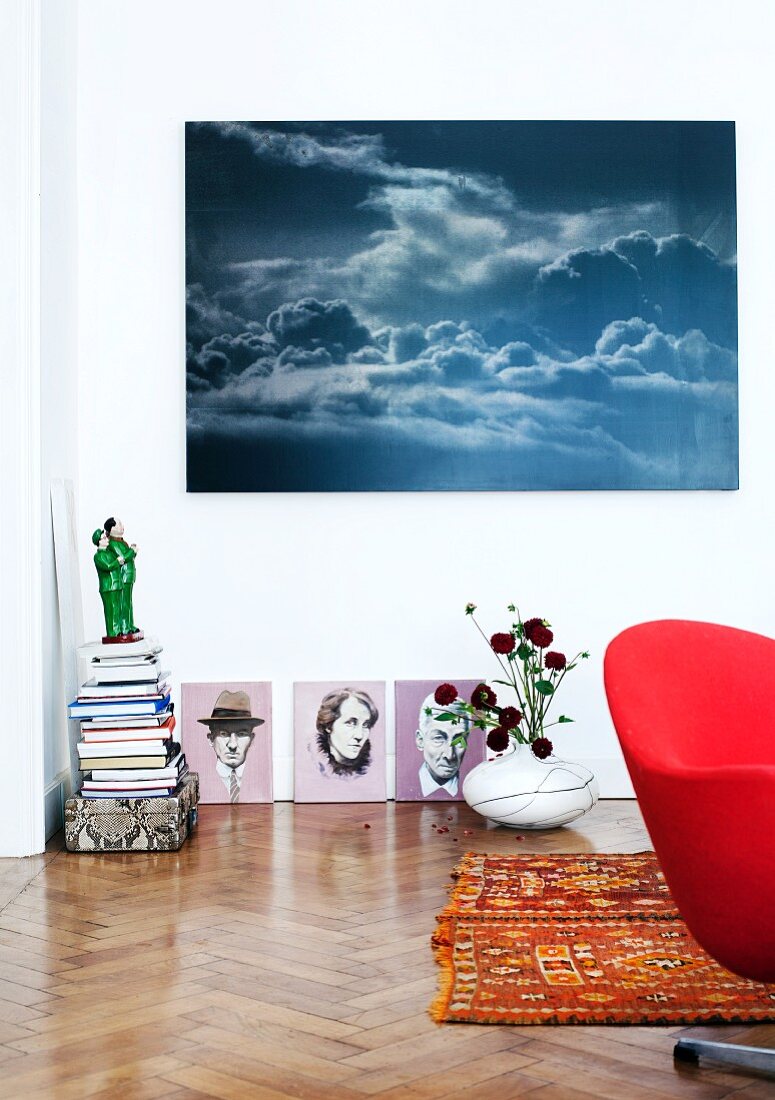 Collection of artworks in corner with small ceramic sculpture and modified portraits from flea market below photo of dramatic sky