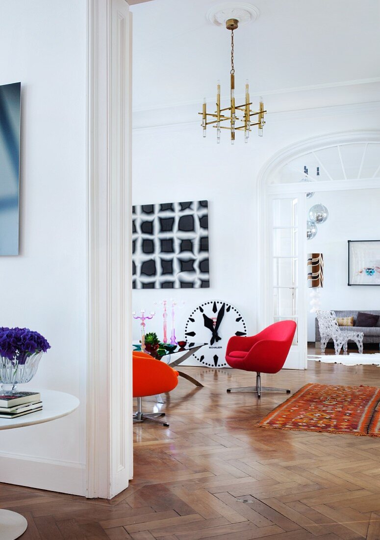 View through three connected rooms in Viennese period apartment with modern artworks and retro and designer furniture