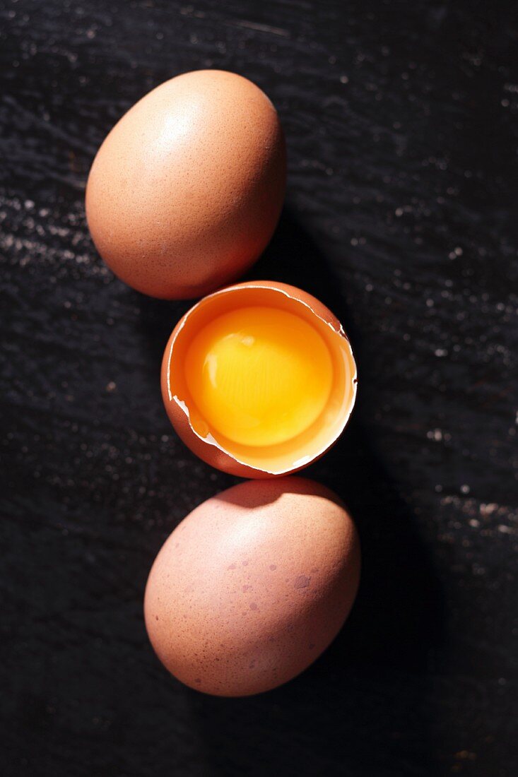 Three brown eggs, open cracked open