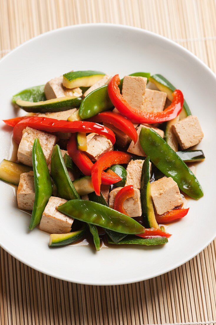 Stir-fried tofu cubes and vegetables (mange tout, courgette and red peppers) with soy sauce