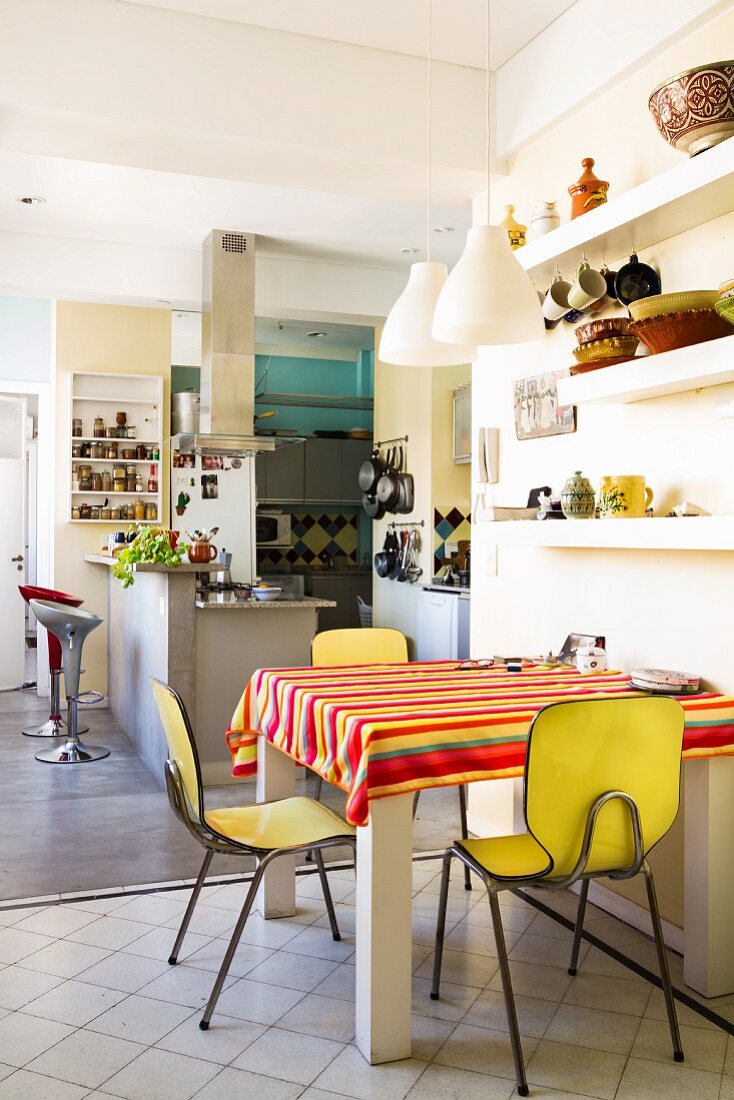 Small dining area with yellow vintage chairs in large kitchen-dining room with breakfast bar in background