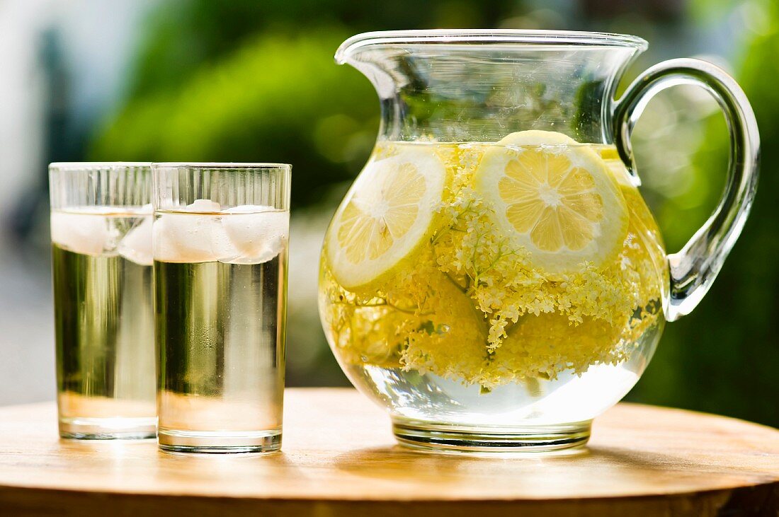 Holunderblütensaft mit Zitronen in Glaskrug und Gläsern