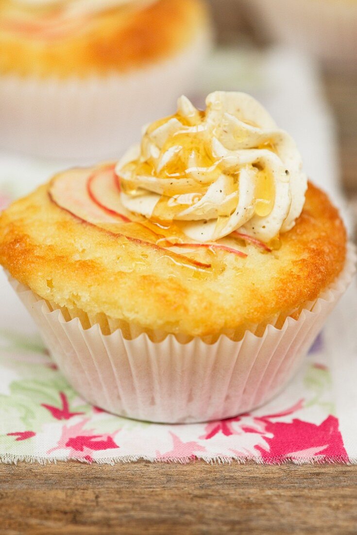 An apple cupcake decorated with buttercream and maple syrup