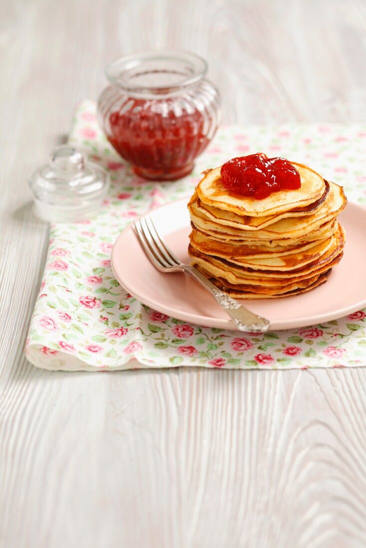 A stack of pancakes with strawberry jam