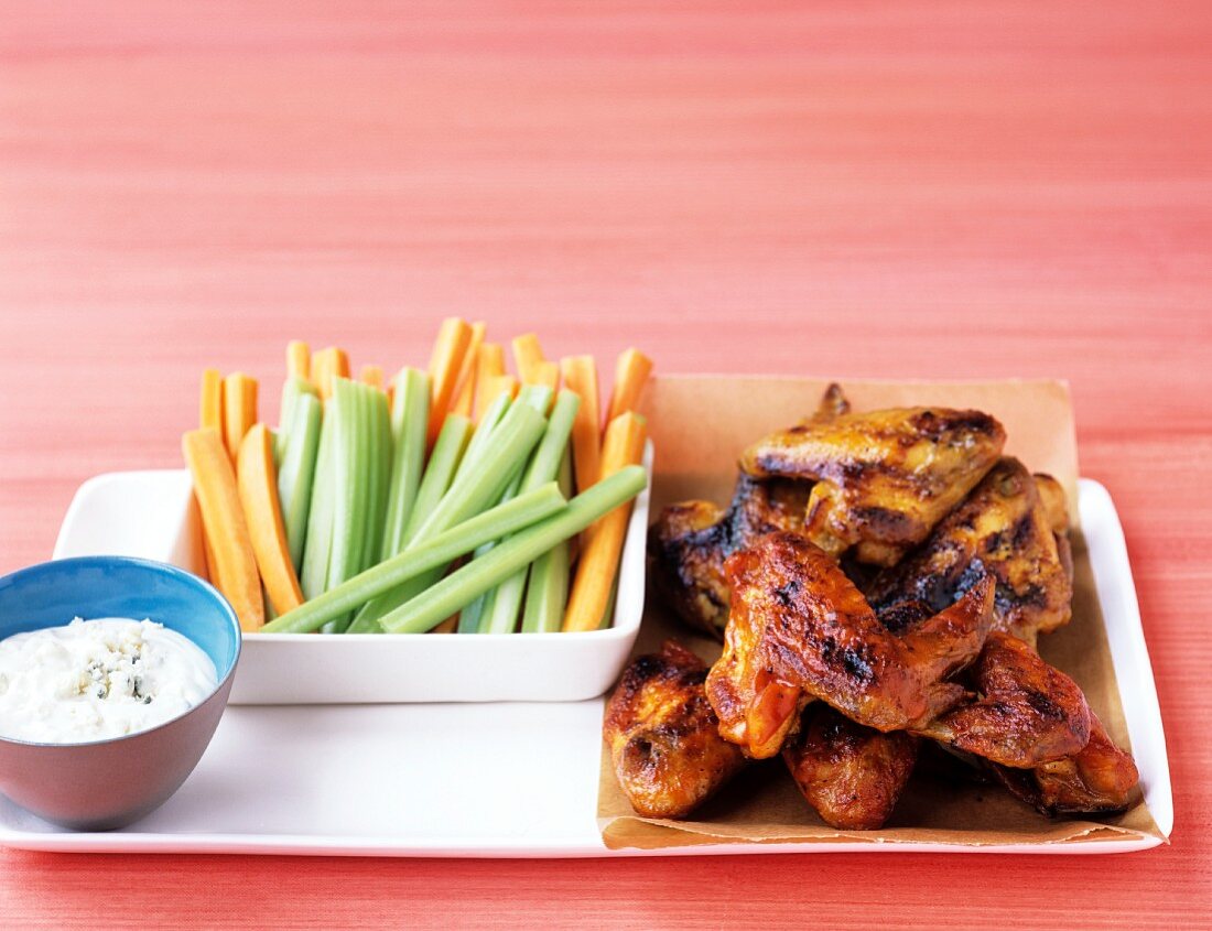 Glazed chicken wings with celery and carrot sticks and a blue-cheese dip