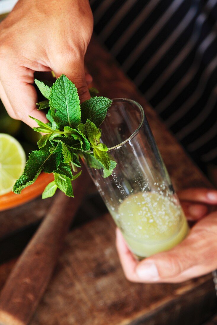 A mojito being made (mint being arranged on the edge of the glass)