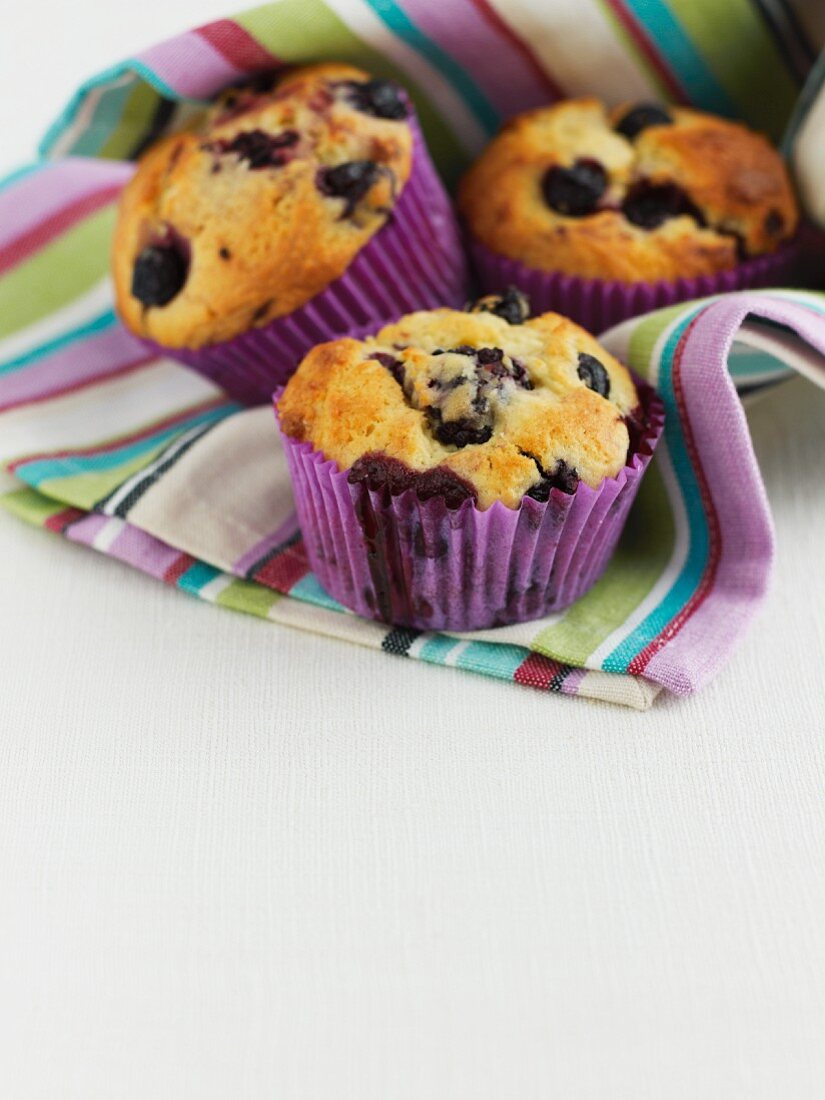 Three blueberry muffins in a stripped cloth