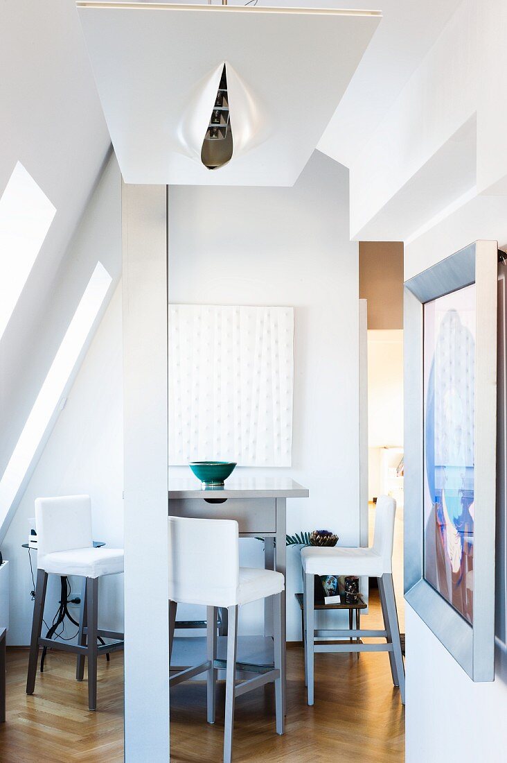 Tall dining counter and bar stools in converted attic with contemporary ceiling light in foreground