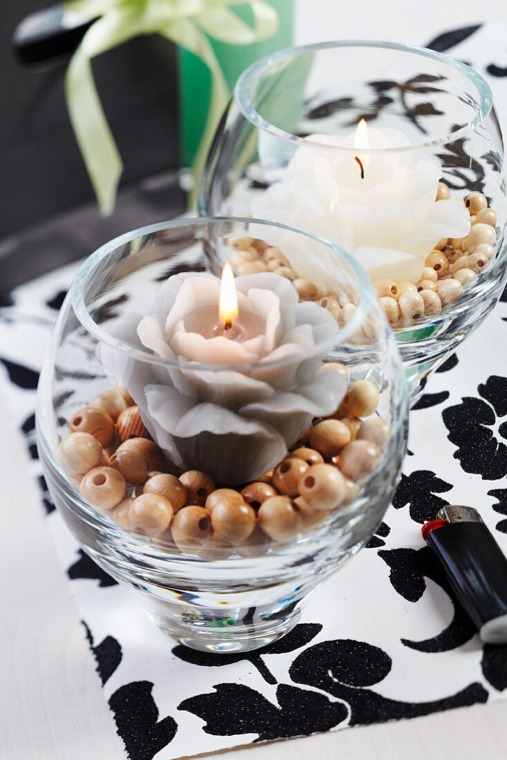 Windlichter mit blumenförmiger Kerze auf Holzperlen und schwarzweisses Tischset