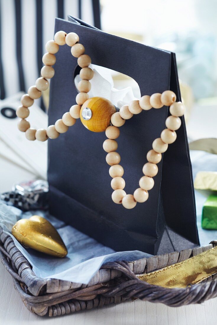 Black gift bag decorated with bow made from wooden beads