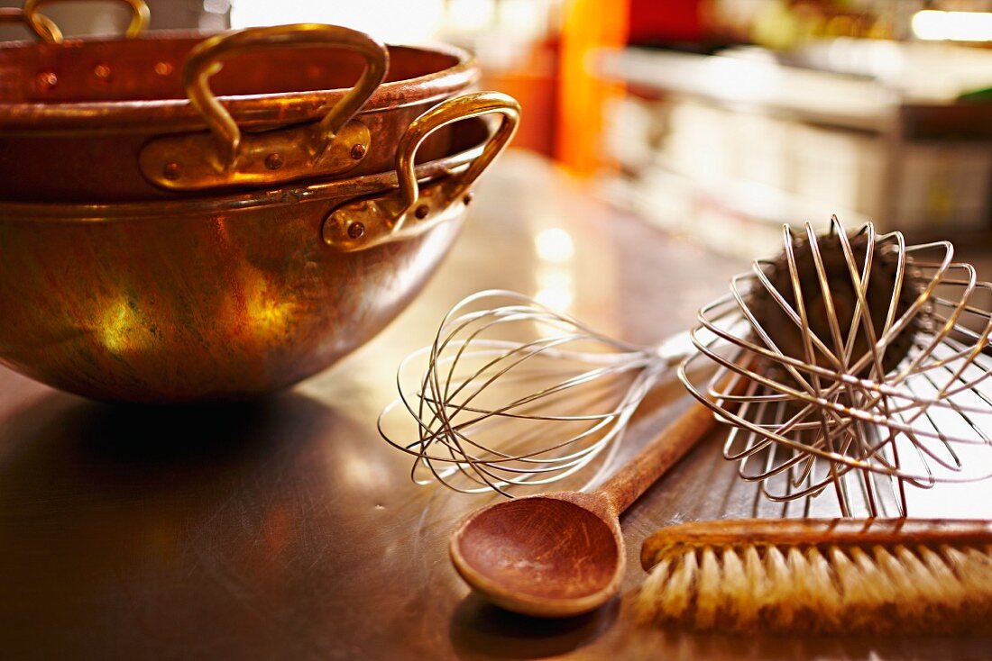 A copper kettle, whisks, a wooden spoon and a brush