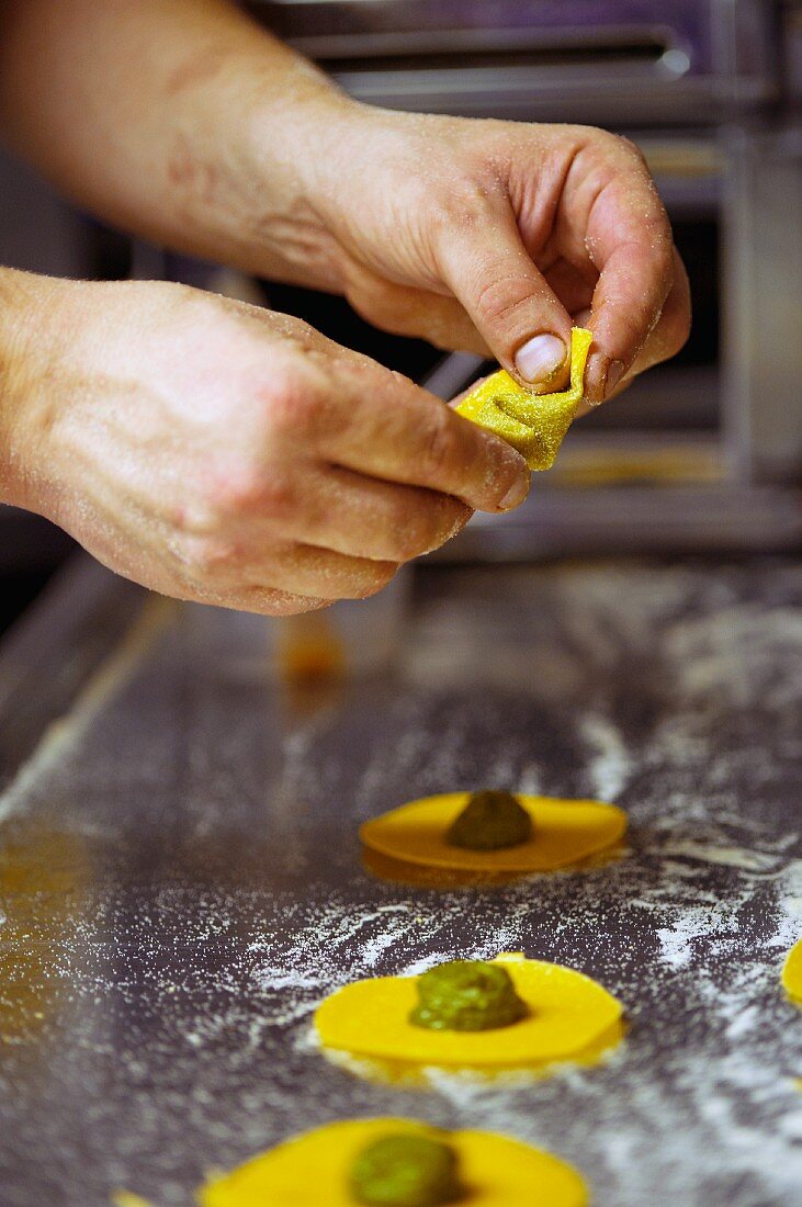 Tortellini being filled with pesto