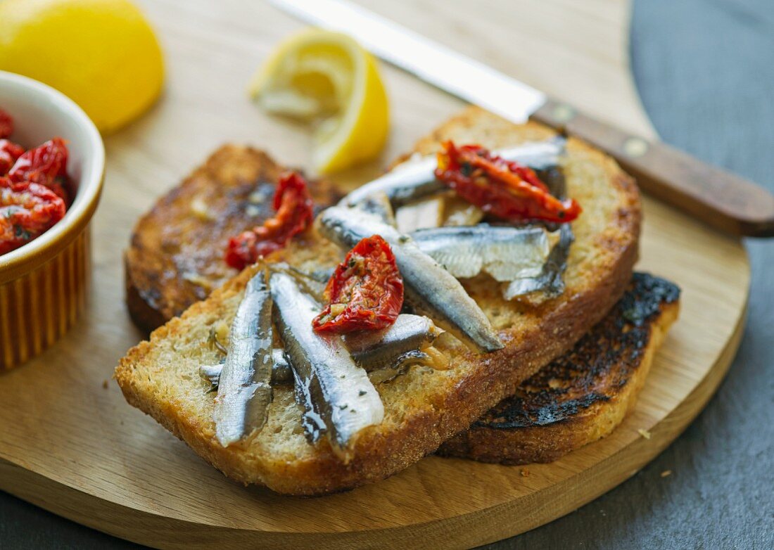 A slice of toast topped with smoked anchovies and dried tomatoes