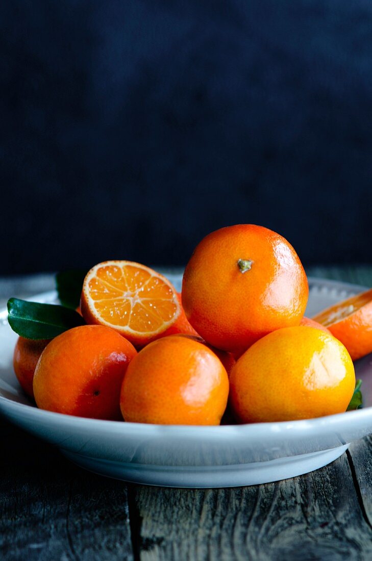 Clementines in a grey bowl on a wooden surface