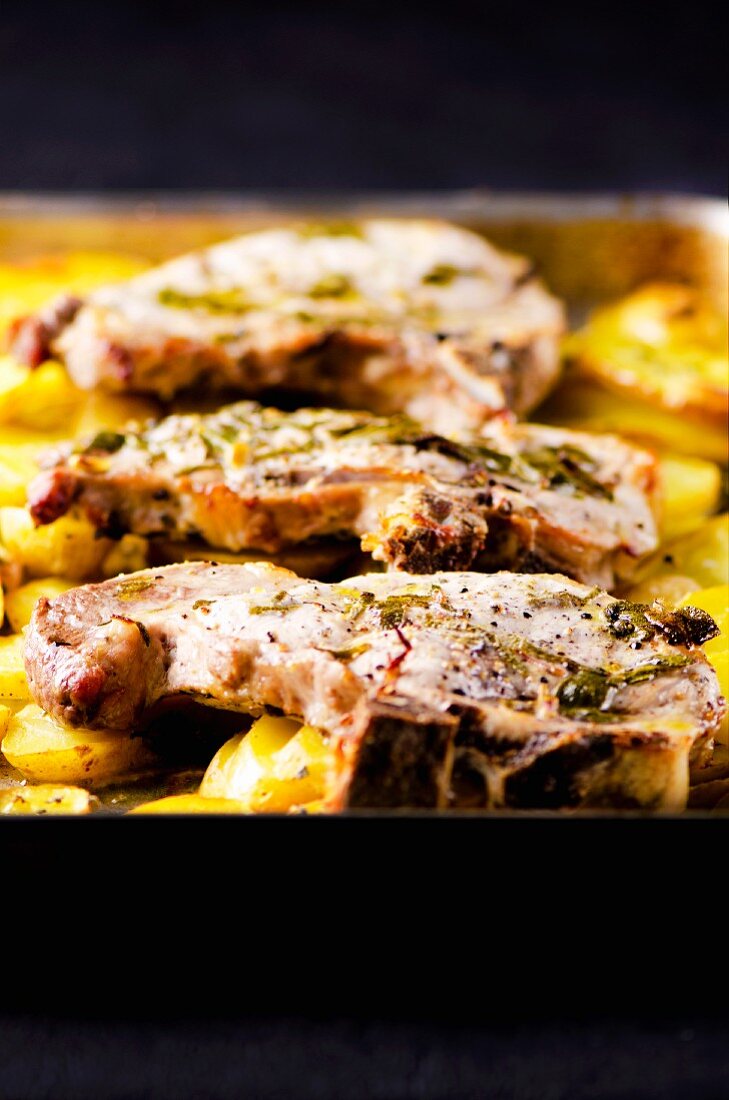 Grilled pork steaks with lemon and sage served on roast potatoes