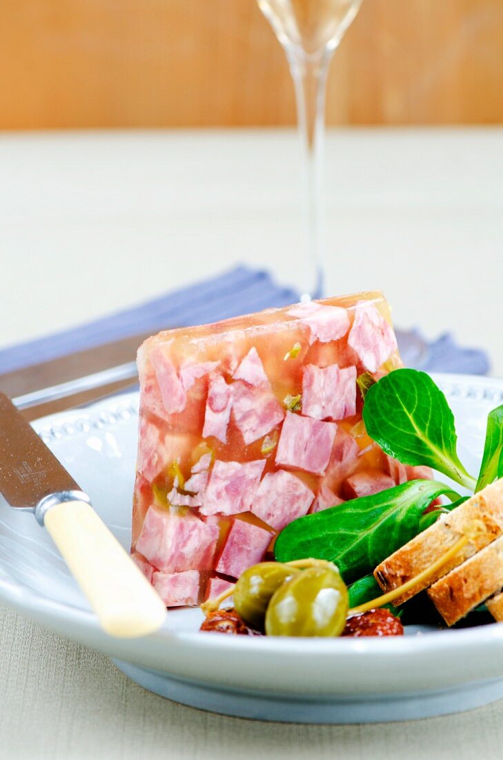 Presswurst mit Riesenkapern, Brotscheiben und Feldsalat