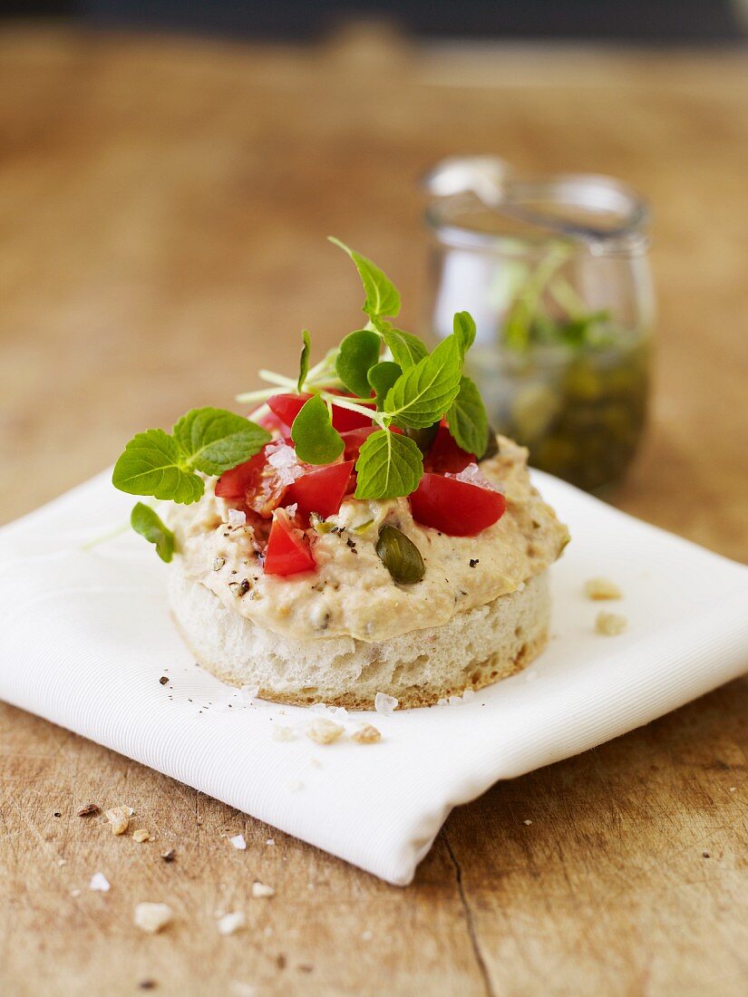 White bread topped with hummus, capers and tomatoes