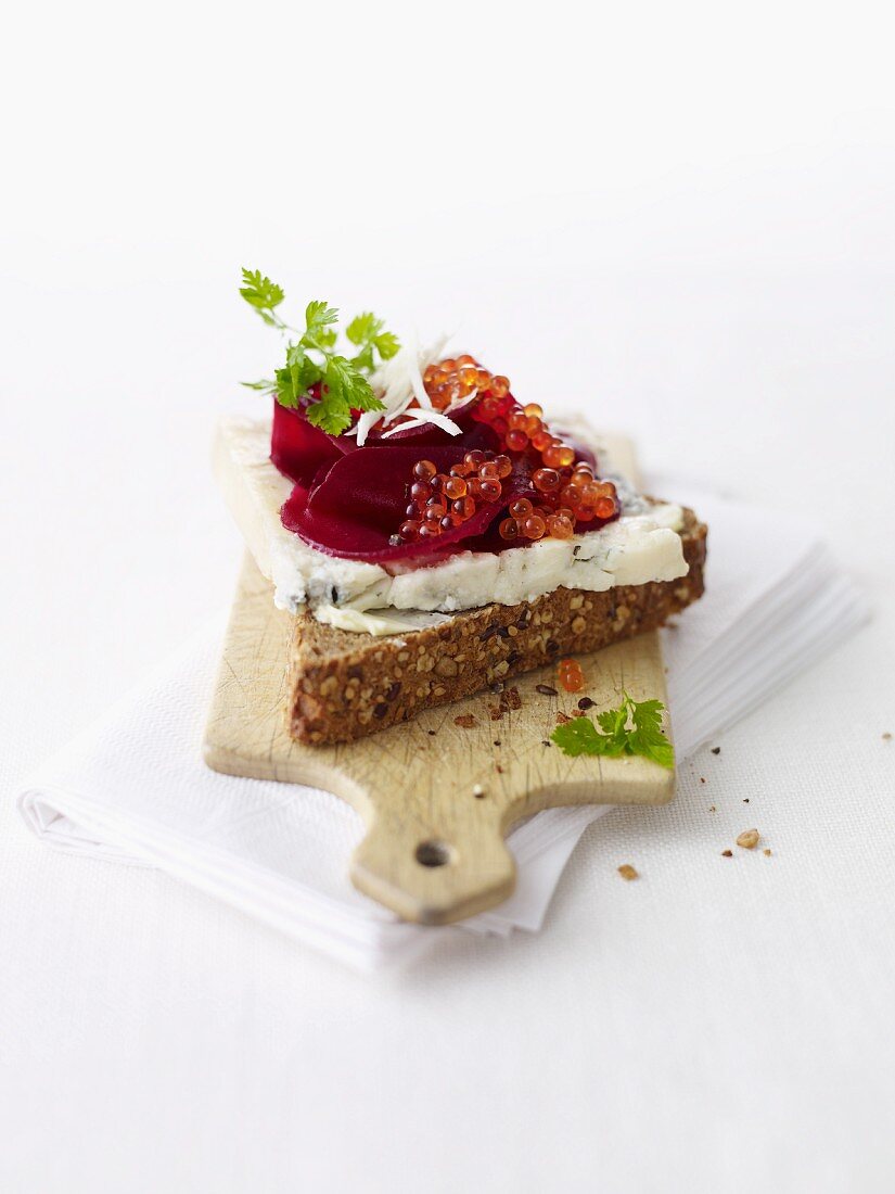 A slice of wholemeal bread topped with blue cheese, beetroot and caviar