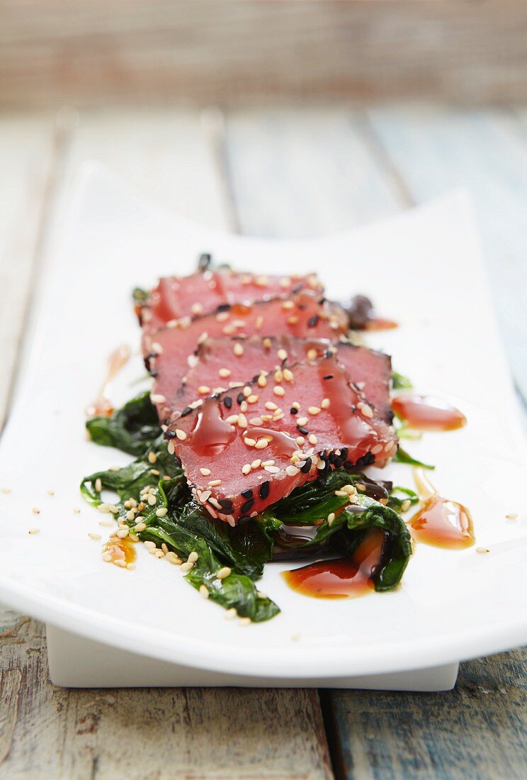 Tuna sashimi with sesame seeds on a bed of spinach
