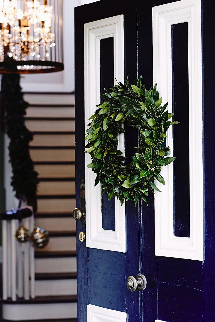 Open blue and white front door decorated with festive Christmas wreath