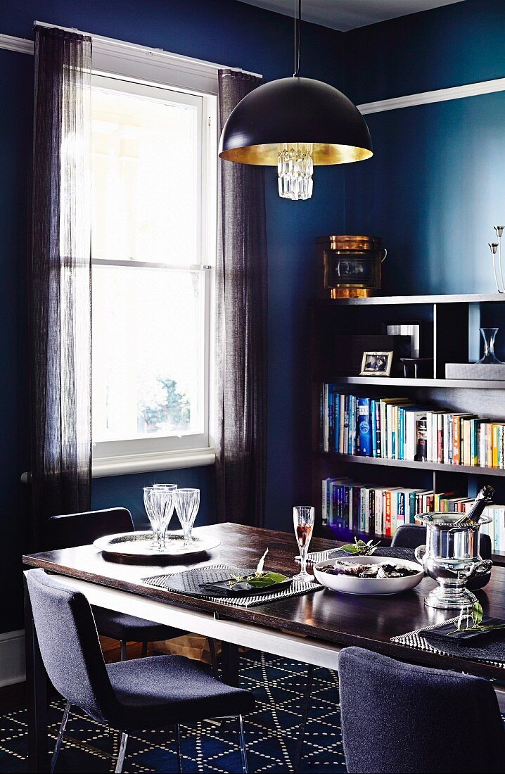 Set table & bookcase in dining room in shades of blue and grey