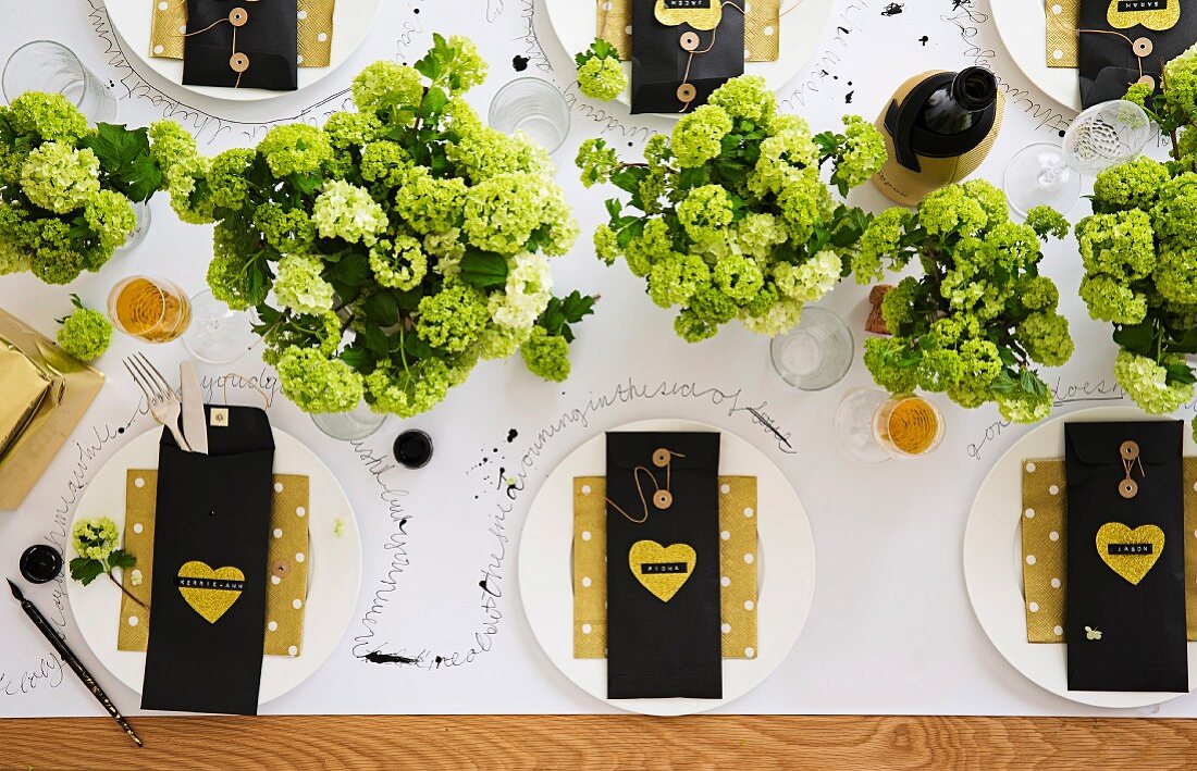 Festively set table decorated with hydrangeas & cutlery in bags